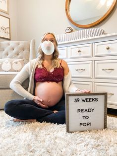 a pregnant woman sitting on the floor with a sign reading 39 weeks ready to pop