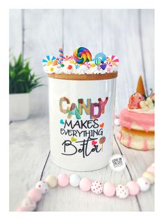 a white mug with candy on it sitting next to some candies and other decorations