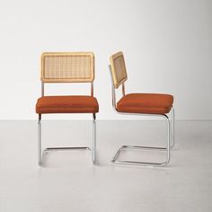 two chairs sitting side by side in front of a white wall and one has an orange seat cushion