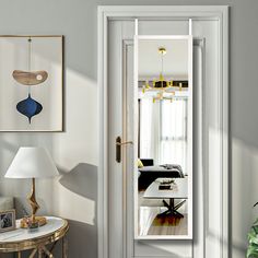 an open door leading to a living room with white walls and wood flooring on the other side