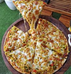 two slices of pizza on a wooden platter with sauce and cheese being lifted from it