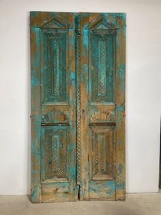 an old pair of wooden doors with intricate carvings on them, against a white wall