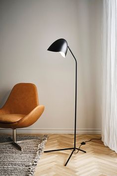 a black floor lamp next to an orange chair