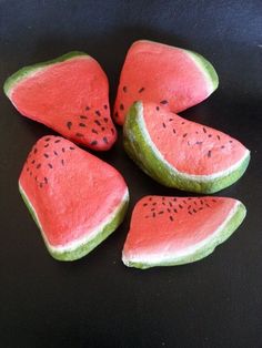 four pieces of watermelon sitting on top of a black surface