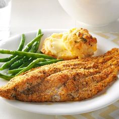 a white plate topped with fish, green beans and mashed potatoes