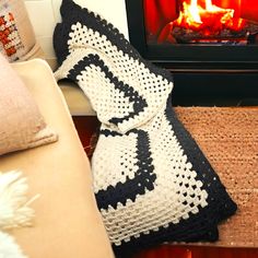 a crocheted afghan sitting next to a fire place with a pillow on it