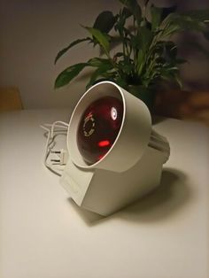 an electronic device sitting on top of a white table next to a potted plant