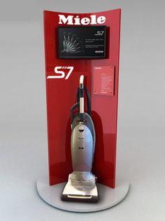 a silver and black vacuum on display in front of a red sign that says miele