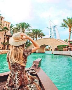 a woman in a leopard print dress and hat sitting on a boat looking out over the water