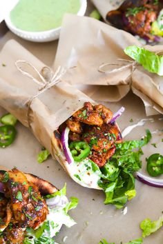 two wraps filled with meat and veggies next to some dipping sauce on the side