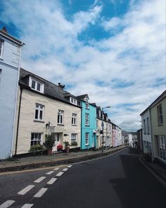 an empty street lined with row houses under a cloudy blue sky