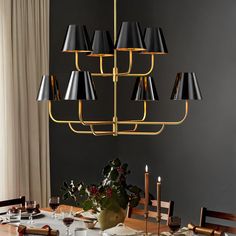 a chandelier hanging over a dining room table with place settings on the table