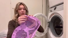 a woman holding up a purple object in front of a dryer