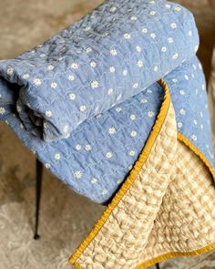 two blue and yellow bedspreads sitting next to each other on top of a chair