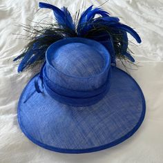 Mad Hatter Kentucky Derby Hat With Feathers And Wide Brim. Blue. String Tightens Head Piece. Kentucky Derby Racetrack Hat. Peacock Like Feathers Adjustable Brimmed Blue Top Hat, Blue Adjustable Boater Hat With Curved Brim, Fitted Blue Brimmed Sun Hat, Adjustable Blue Boater Hat With Curved Brim, Blue Fedora For Summer Parties, Blue Wide Brim Fedora For Kentucky Derby, Blue Summer Fedora For Parties, Blue Summer Party Fedora, Blue Straw Hat With Short Brim