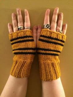 two hands wearing yellow and black knitted fingerless gloves with silver rings on them