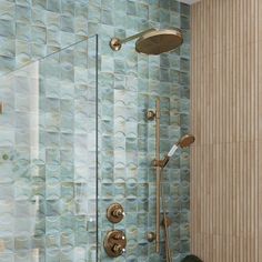 a bathroom with blue and green tiles on the wall, shower head, and hand held shower faucet