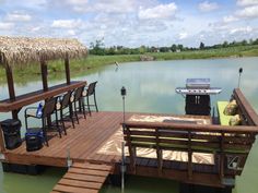 a dock that has chairs and tables on it in the water next to some grass huts