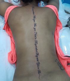 a woman laying on top of a bed with her back turned to the camera and tattoo