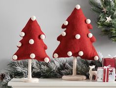 two red christmas trees sitting on top of a mantle