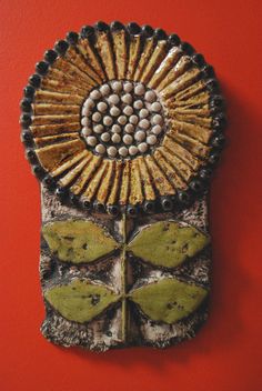 a close up of a decorative object on a red wall with a butterfly and flower design