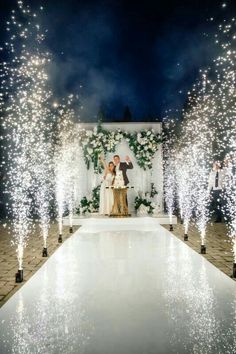 two people standing on a runway surrounded by sparklers