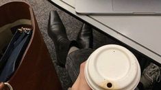 a person holding a coffee cup next to a laptop