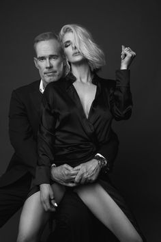 a man sitting next to a woman on top of a chair in front of a black background