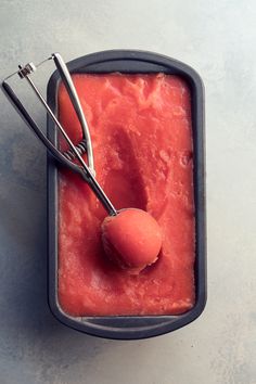 a scoop of ice cream in a metal container with a pair of tongs on top