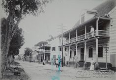 an old black and white photo of people walking in front of buildings with balconies