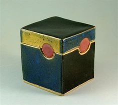 a small black and blue box with two red circles on the top, sitting on a white surface