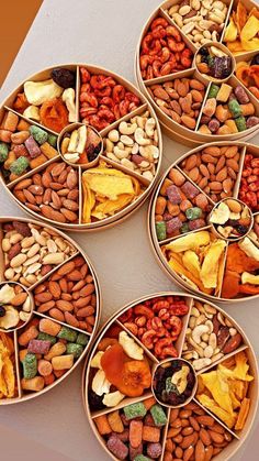 four bowls filled with different types of nuts and dried fruits on top of a table