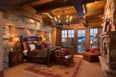 a large bedroom with stone walls and wood ceilinging, along with a fireplace in the corner