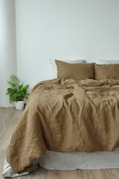 a bed with two pillows and a blanket on top of it in a white room