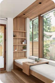 a room with some bookshelves and two benches in front of large windows that look out onto the yard