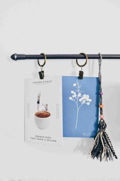 two books are hanging on the wall with tassels attached to them and one is holding a cup of coffee