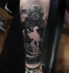 a man's arm with a diving helmet tattoo on it