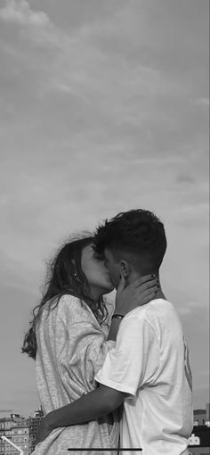 a man and woman kissing in front of a city skyline