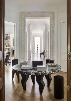 an elegant dining table in the middle of a room with wood flooring and white walls