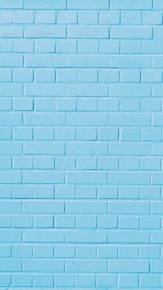 a blue brick wall that is painted in different shades and sizes, with one light blue color