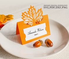 an orange and white place card with acorns on it sitting on a plate