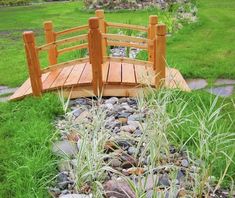 a wooden bridge over some rocks and grass