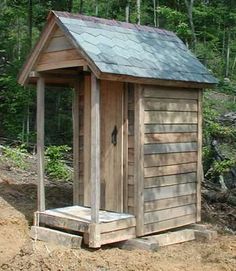 a small wooden outhouse in the woods