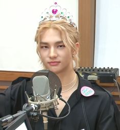 a woman wearing a tiara sitting in front of a microphone with a sticker on it