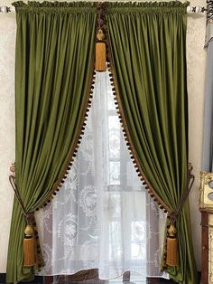 a green curtain with tassels hanging from it's sides in front of a window