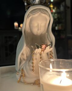 a white statue sitting next to a lit candle