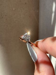 a person holding a diamond ring in their hand with the light shining on it's side