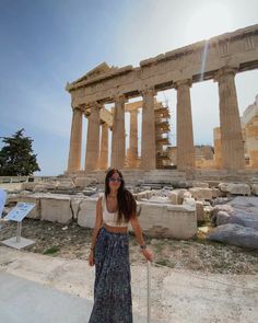 a woman standing in front of the parthenion with her hand on a stick