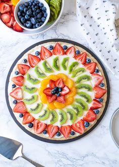 the fruit pizza is decorated with kiwis, strawberries and blueberries