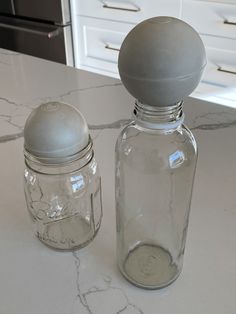 two glass jars sitting on top of a kitchen counter next to each other with lids